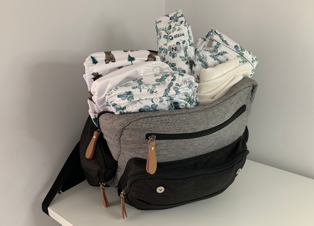 Nappy bag for baby packed with reusable nappies, wipes, wet bag, and changing mat.