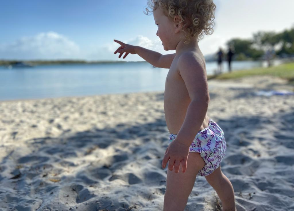 baby on beach wearing colourful swim nappy 