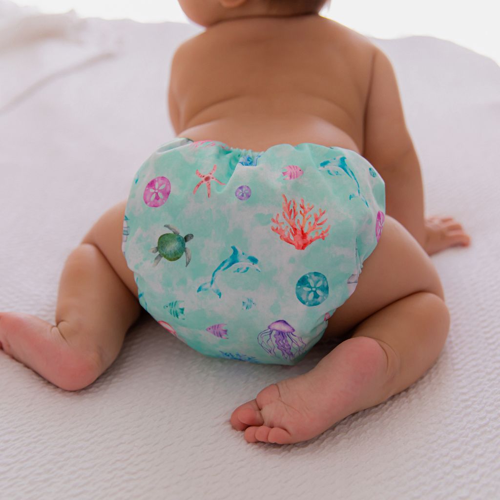 Baby on all fours wearing an oceanic themed cloth nappy 