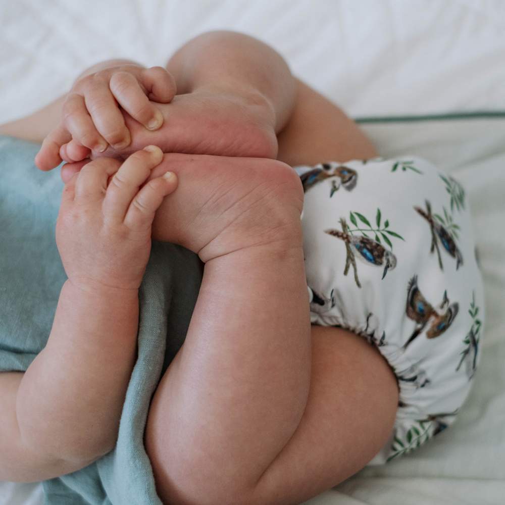 Baby holding feet up and wearing reusable nappy