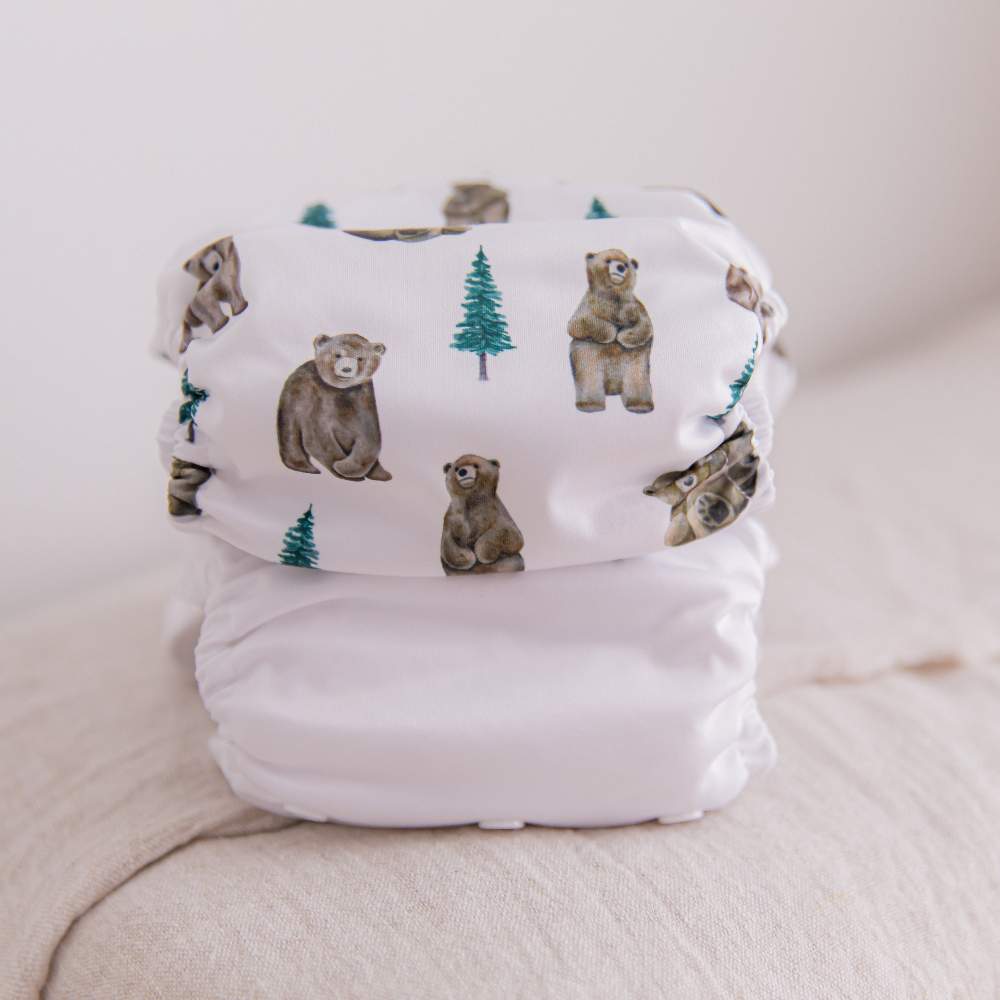 Stack of reusable nappies on the end of the bed: white and bear cub prints