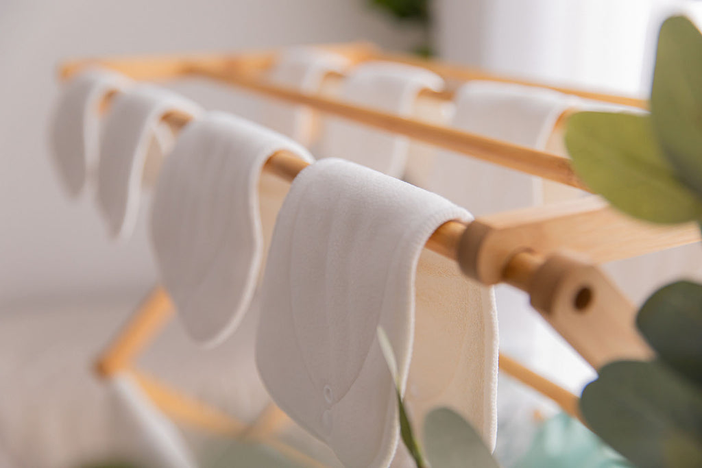 A close up of cloth nappy inserts drying on a bamboo clothes drying rack