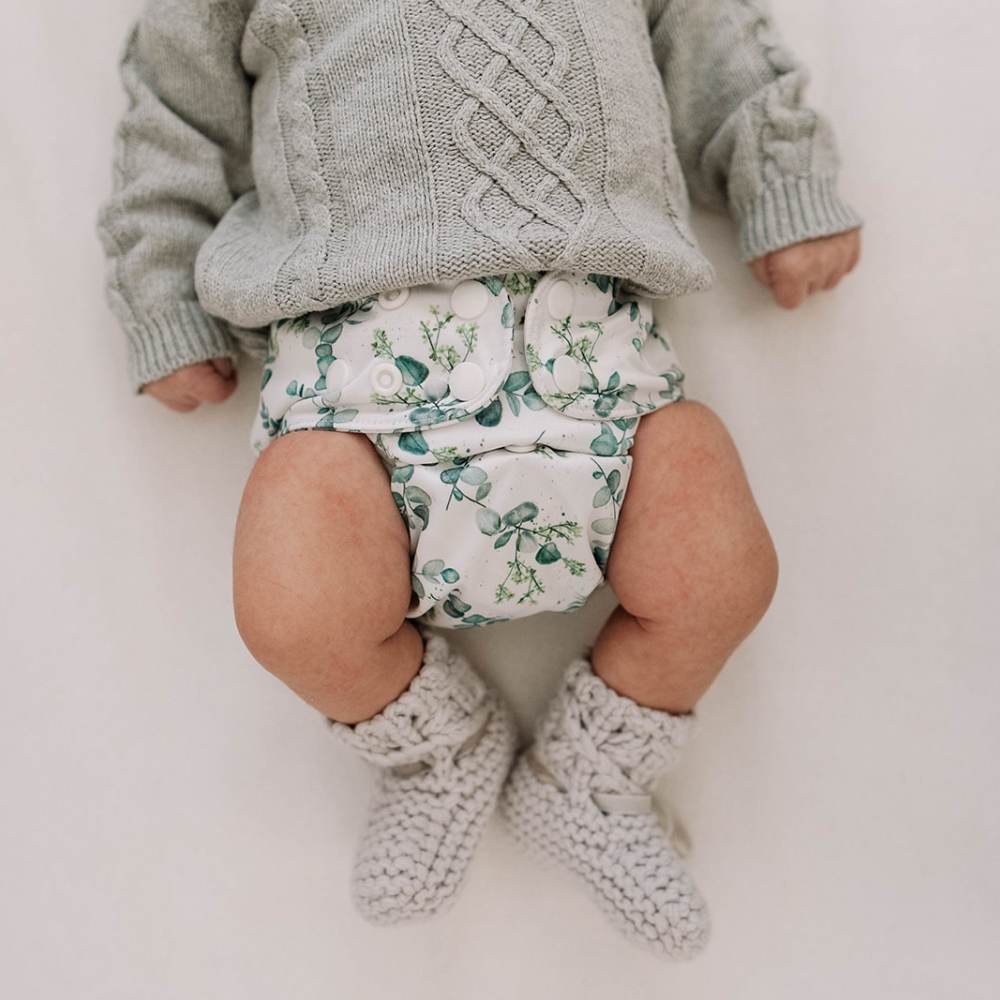 Newborn baby wearing cute grey wooly jumper and booties, with eucalyptus reusable nappy