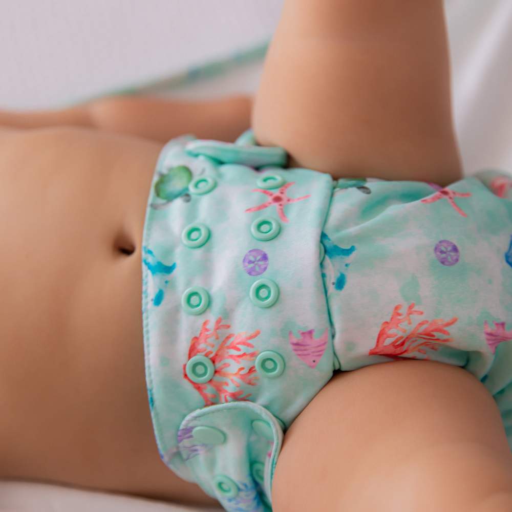 Close up of toddler wearing oceanic cloth nappy laying on top of oceanic change mat