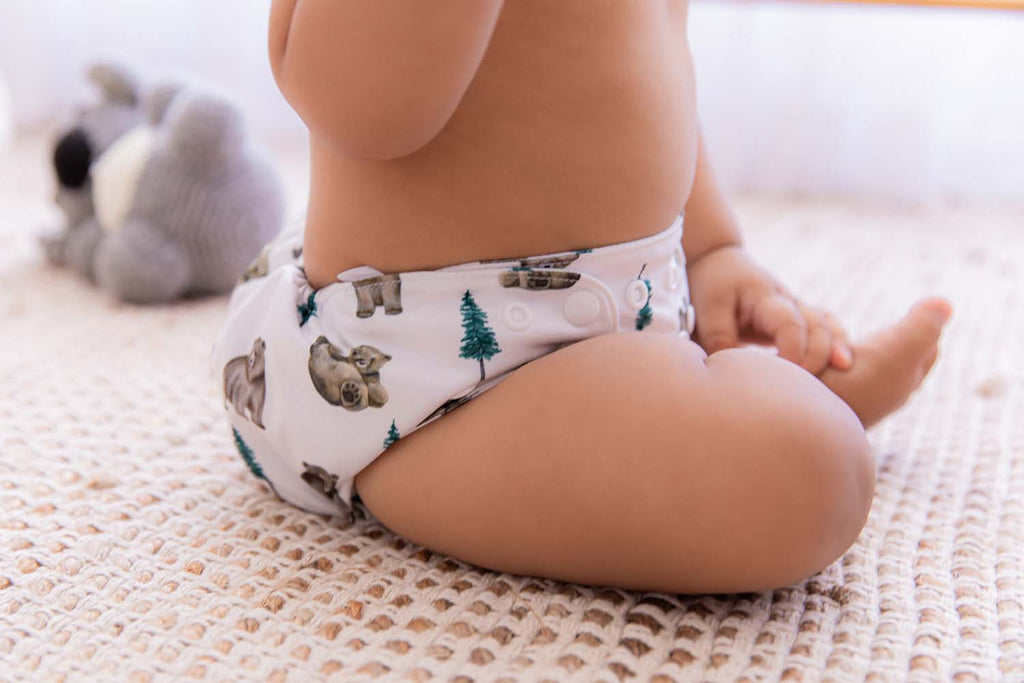 Close up of baby sitting up in white bear cub cloth nappy