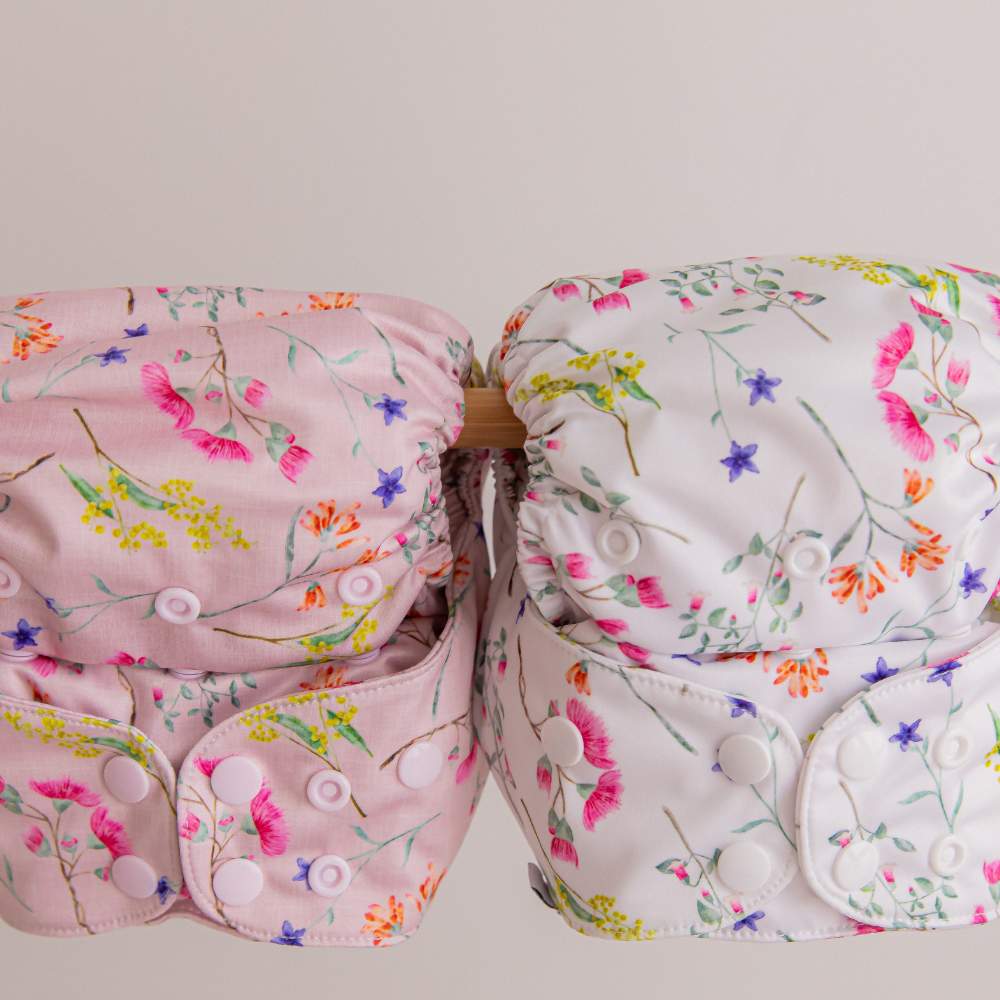 2 floral australian themed reusable nappies hanging on wooden rail