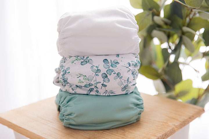 Stack of three cloth nappies on a side table with plan in the background. 