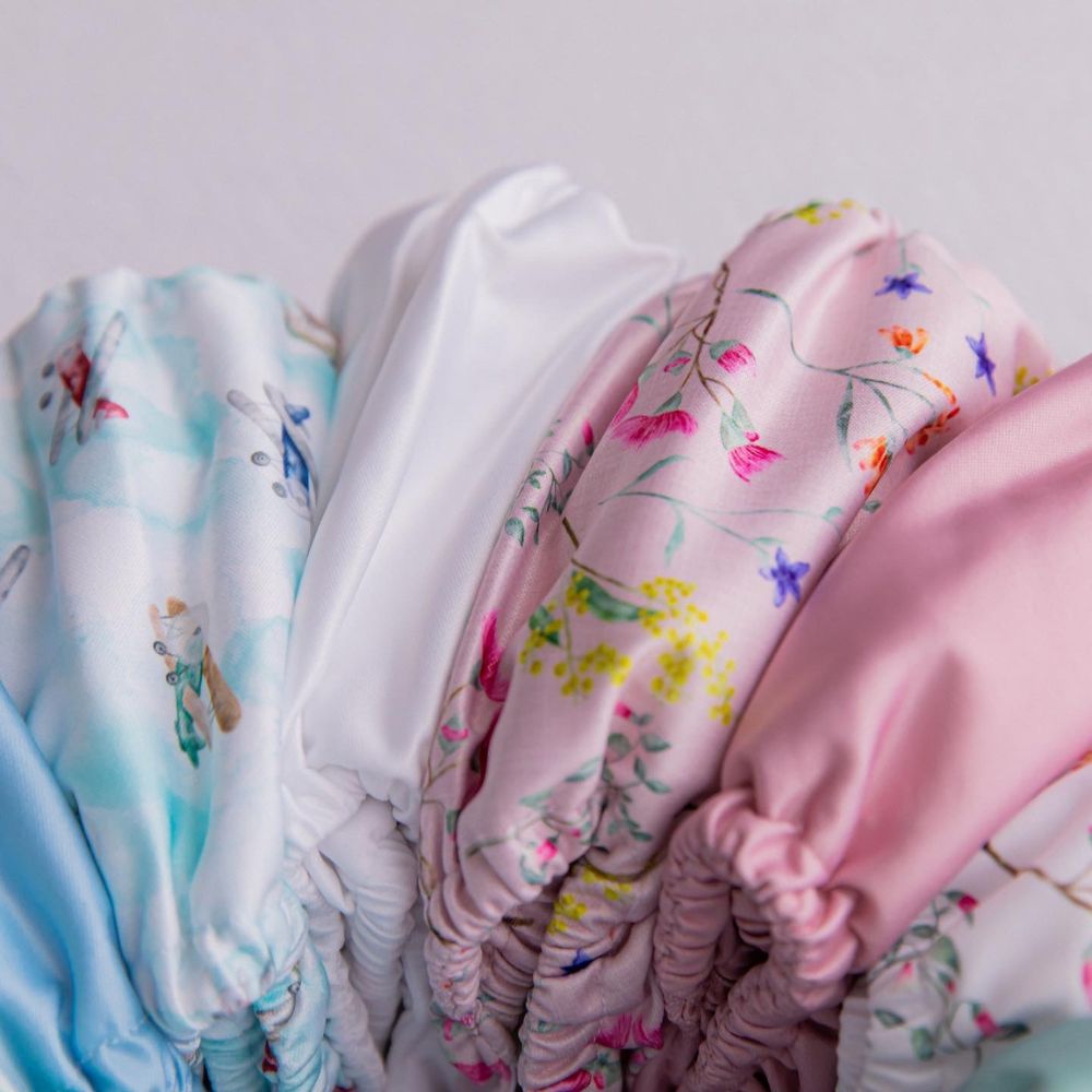 Image shows an arch of reusable nappies of various colours and prints
