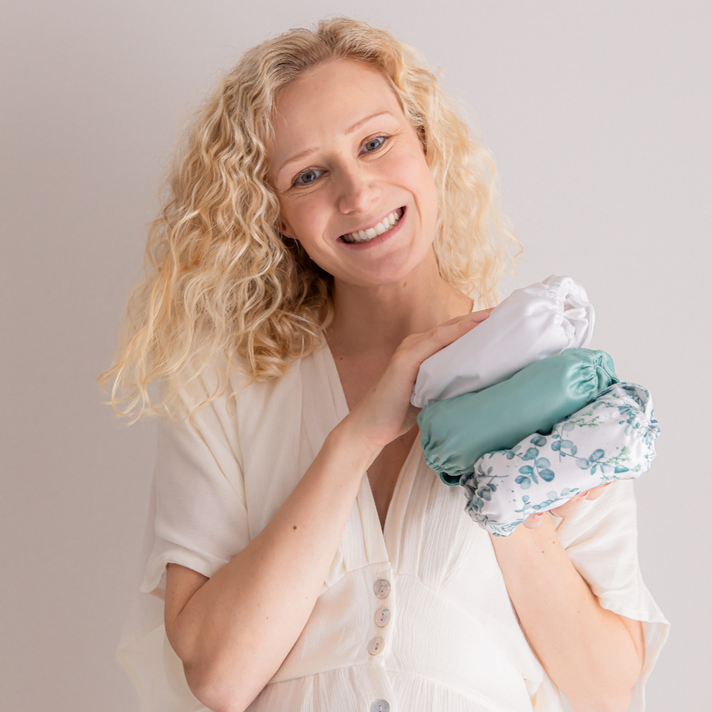 Woman smiling and holding 3 modern cloth nappies