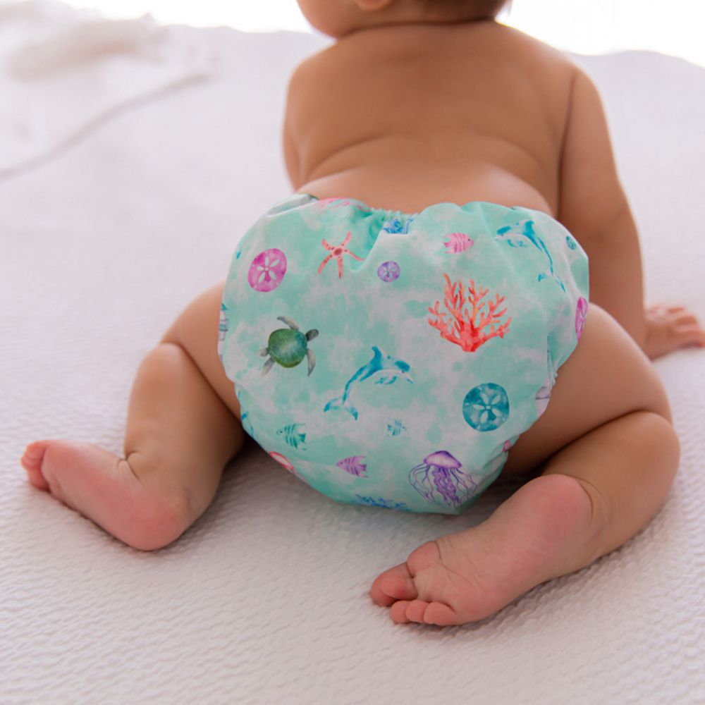 Picture of cute baby on hands and knees facing away from camera, wearing oceanic cloth nappy